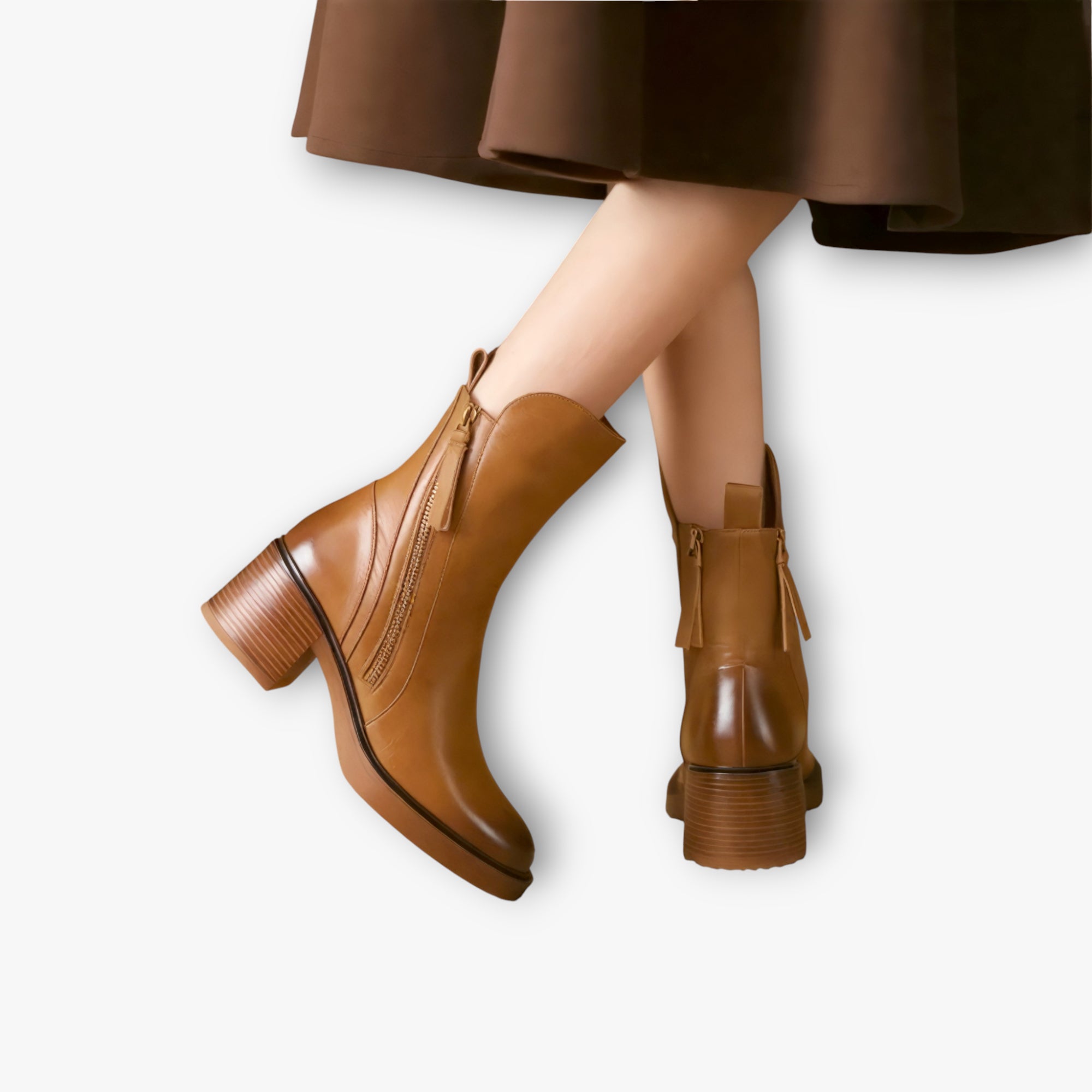 Brown leather ankle boots worn with a brown skirt on a white background