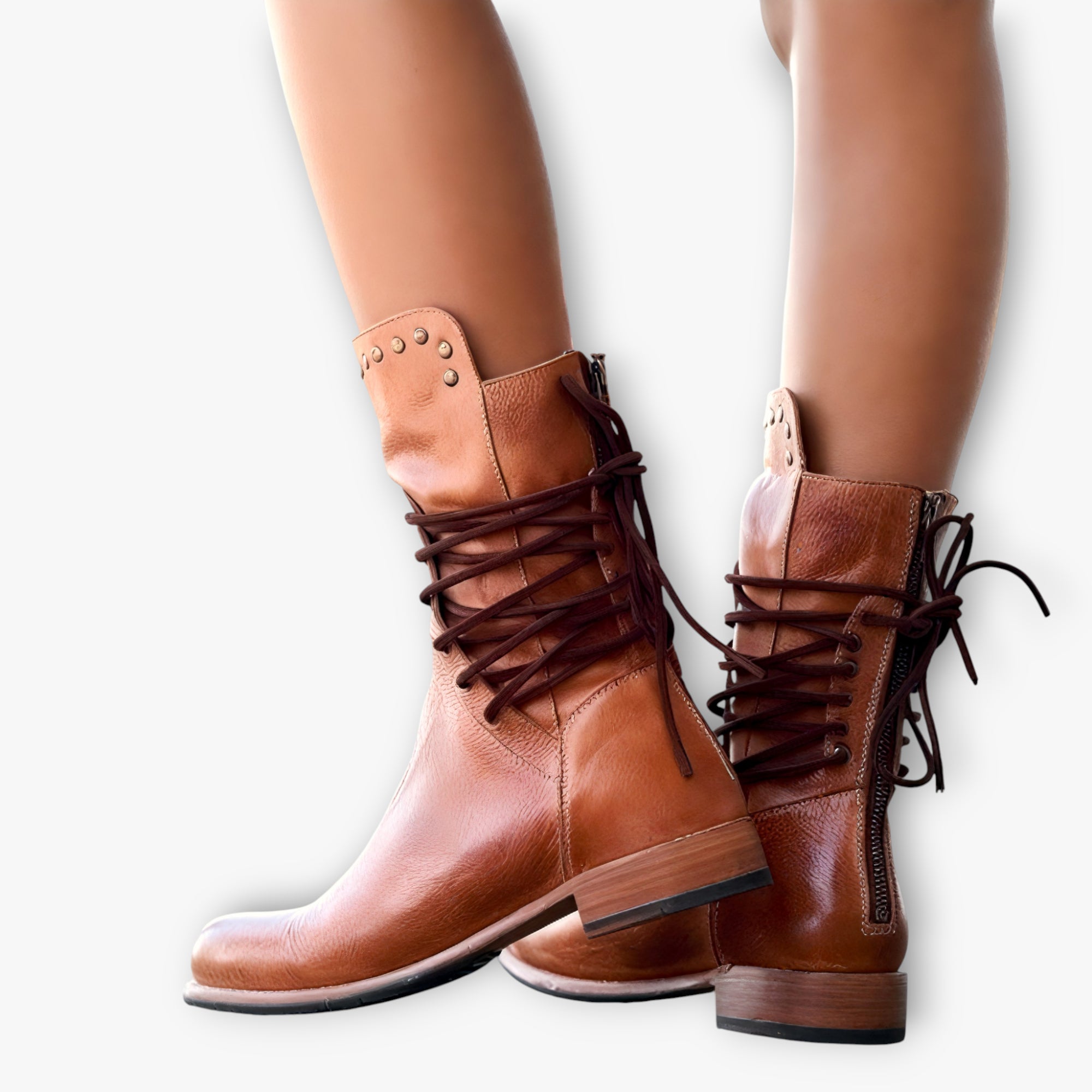 Brown leather boots with laces worn by a person on a white background