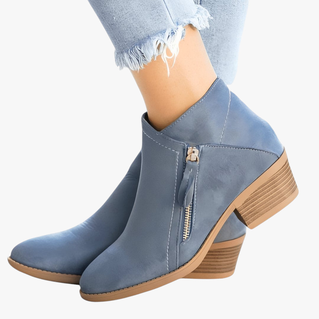 Blue ankle boots with brown soles worn with light blue jeans on a white background